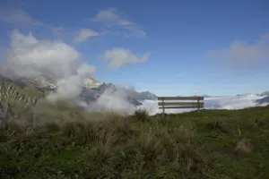 A bench high in the mountains on the Tsjenalp. There are clouds below it.