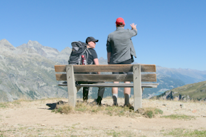 Two individuals at a bench, enjoying the mountain scenery.